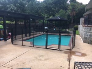Black removable pool safety barrier with a self-closing self-latching, key lockable gate in Grapevine, TX